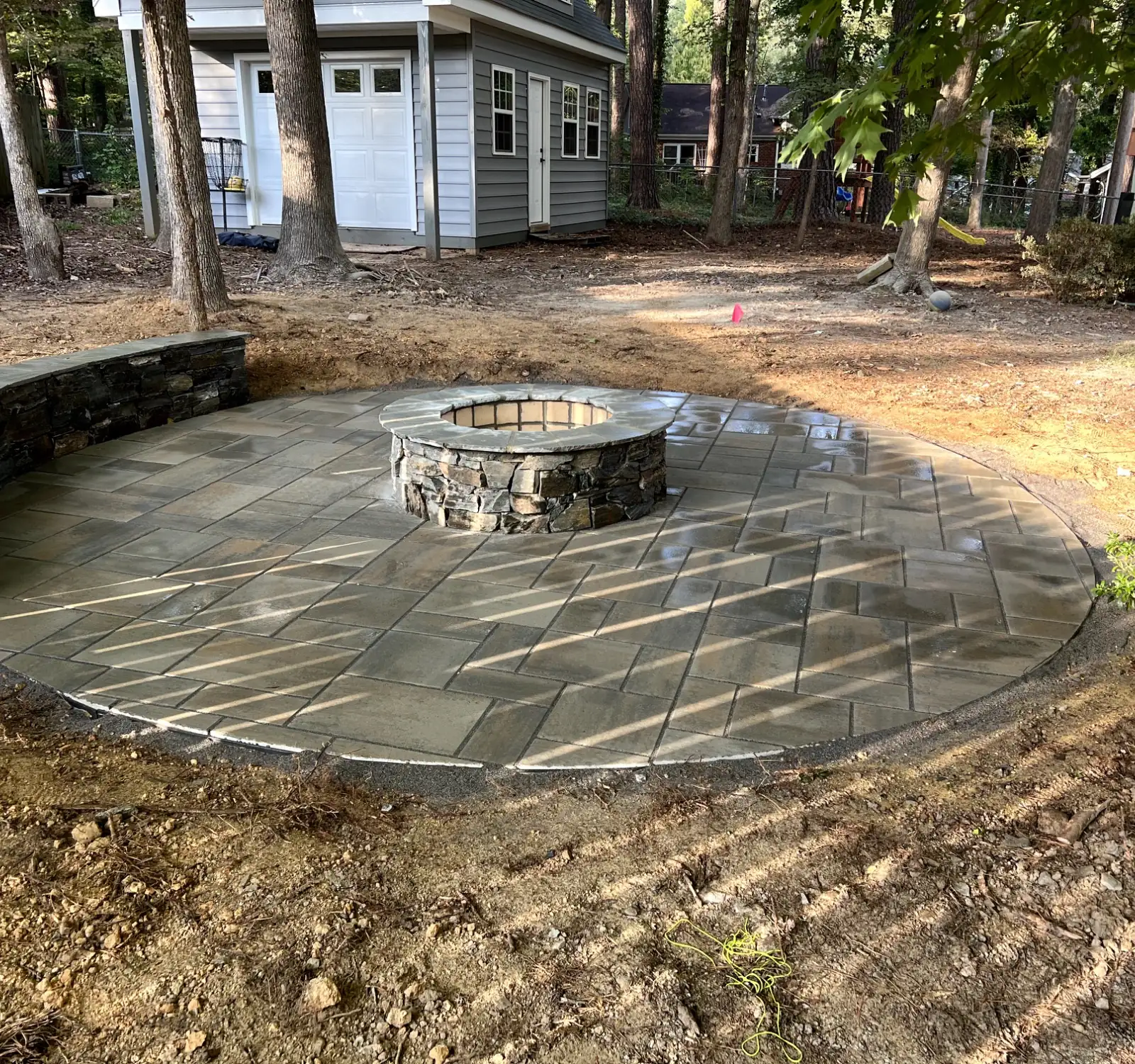 Stone fire pit set into a paver patio, built by Tudi Stone Masonry